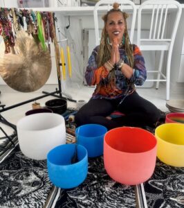 Michele sits in from of colorful sound bowls
